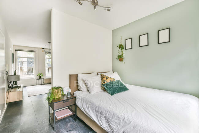 Современная спальня и гостиная интерьер с подушками на одеяло между растениями в доме с плиткой пола — стоковое фото