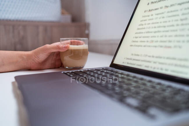 Обрізана невпізнавана жінка-блогер за столом з нетбуком і кавою — стокове фото