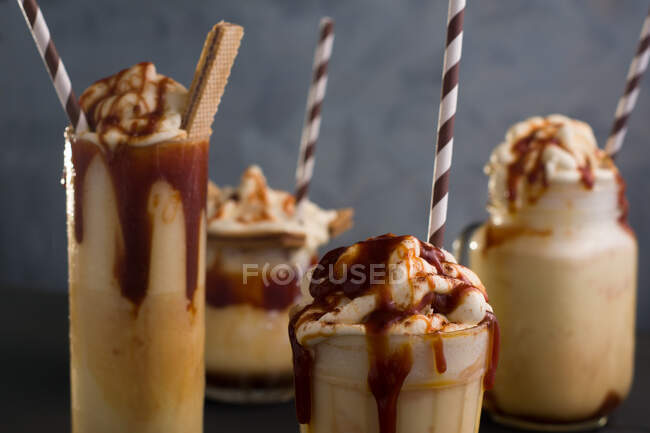 Assorted glasses with sweet caramel milkshake with vanilla ice cream and wafer cookies served on table — Stock Photo