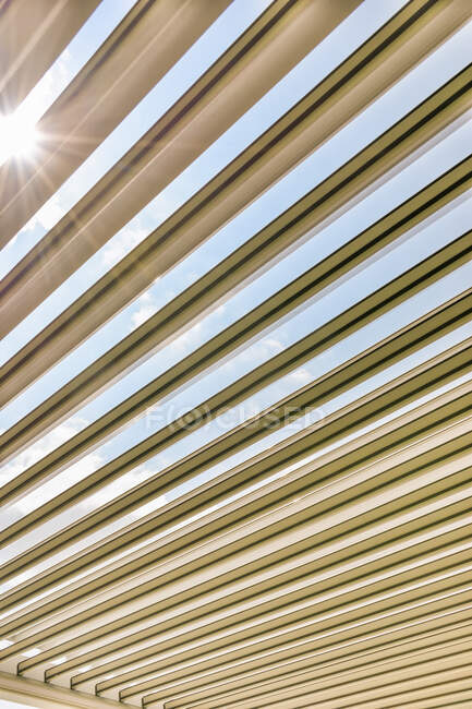 De abaixo da luz solar brilhante que brilha embora os painéis de telhado de madeira da zona de estar da casa contemporânea — Fotografia de Stock