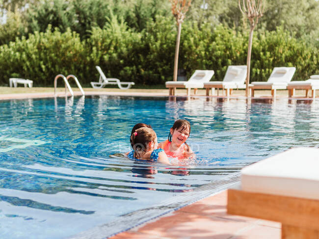 Gruppe fröhlicher Kinder in Badebekleidung schwimmt im Pool, während sie zusammen Spaß haben und die Sommerferien genießen — Stockfoto
