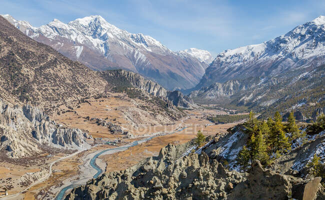 Живописный пейзаж извилистой реки, протекающей между высокими крутыми горами со снежными вершинами в высокогорье Непала — стоковое фото