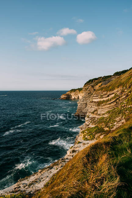 Scenic view of rock against rippled sea with foam and horizon under cloudy blue sky in Saint Jean de Luz — Stock Photo