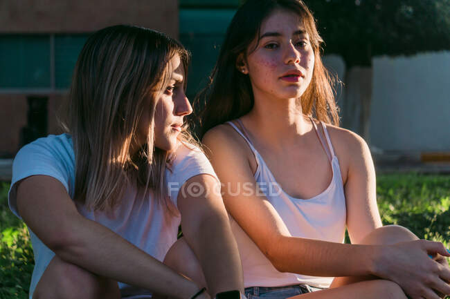 Серйозні найкращі друзі-жінки сидять на тротуарі в літньому парку — стокове фото