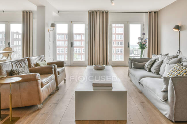 Poltronas confortáveis e sofá colocado em espaçosa sala de estar com interior minimalista em apartamento de luxo à luz do dia — Fotografia de Stock