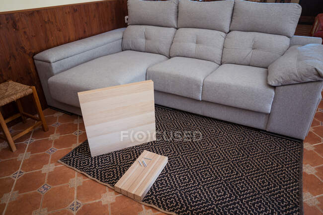 Стільниця і столові ніжки з гвинтами на декоративному килимі проти дивана в кімнаті легкого будинку — стокове фото