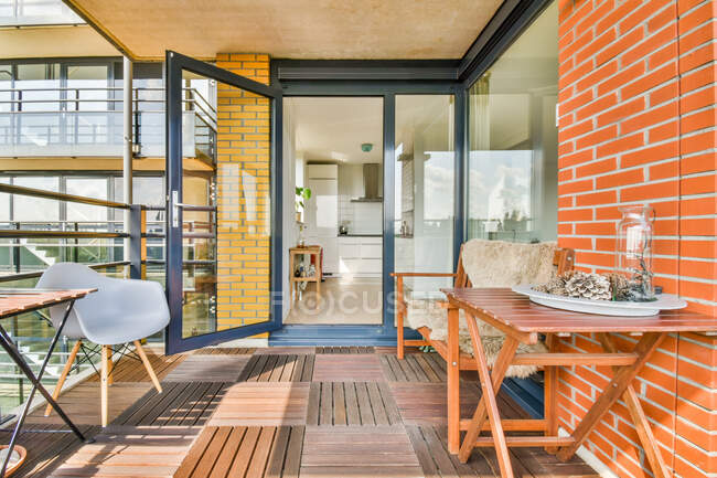 Plateau avec vase et cônes de pin sur la table entre mur de briques et fauteuil sur la terrasse — Photo de stock