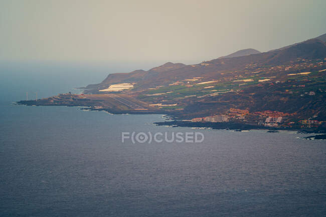 Pequeño aeropuerto construido junto al mar y rodeado de montañas con casas y plantaciones de plátanos. Cumbre Vieja erupción volcánica en La Palma Islas Canarias, España, 2021 - foto de stock
