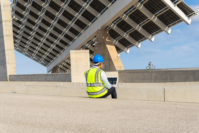 Anonymous male supervisor in uniform working on netbook sitting near solar power station — Stock Photo