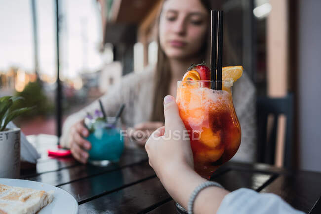Crop content best female friends with tasty beverages in street cafeteria — Stock Photo