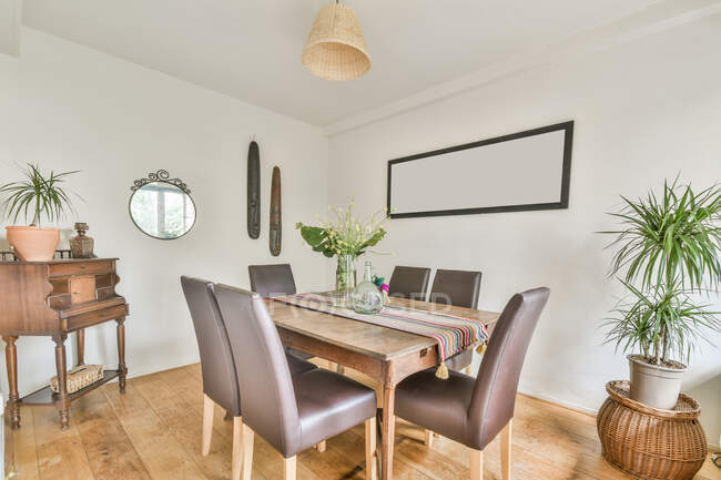 Intérieur de la salle à manger confortable avec table en bois et chaises en cuir souple dans un chalet conçu dans un style rustique — Photo de stock