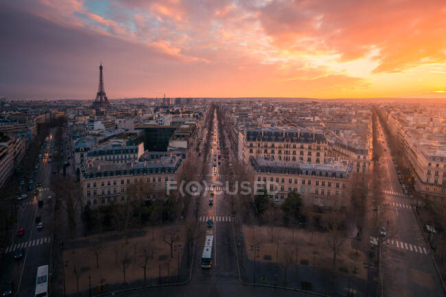 Вид на фасади міського будинку і проїжджання з транспортом під блискучим хмарним небом у Парижі. — стокове фото