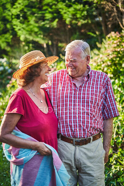 Gentile coppia di anziani accarezzare guardando lontano con tenerezza mentre in piedi vicino arbusti in natura — Foto stock