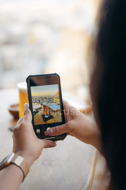 Cortar anônimo cliente feminino tirar foto com telefone celular de cerveja e lanches no bar — Fotografia de Stock
