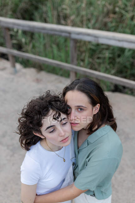 From above of trendy young woman with homosexual beloved looking at camera on bridge — Stock Photo