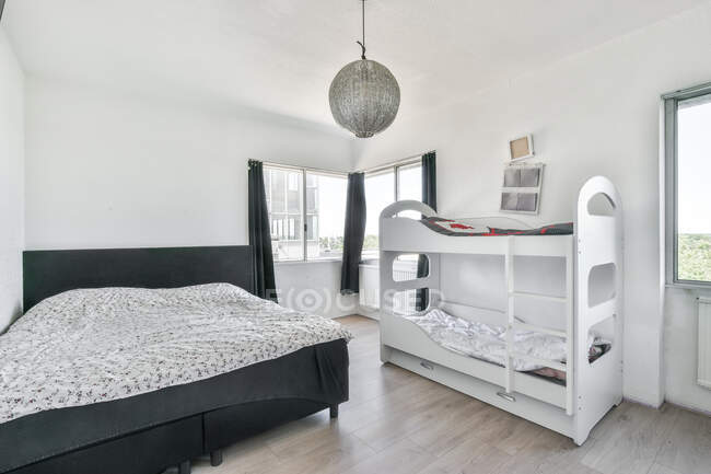 Modernes Interieur des Schlafzimmers mit schwarzem Bett und weißem Etagenbett im minimalen Stil — Stockfoto