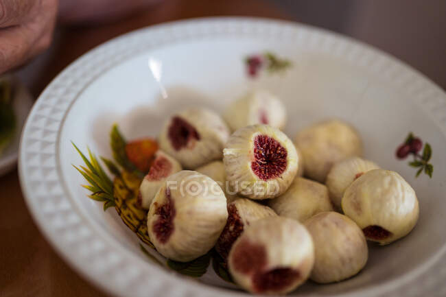 Figos maduros com polpa suculenta em placa de cerâmica com ornamento em casa no fundo borrado — Fotografia de Stock