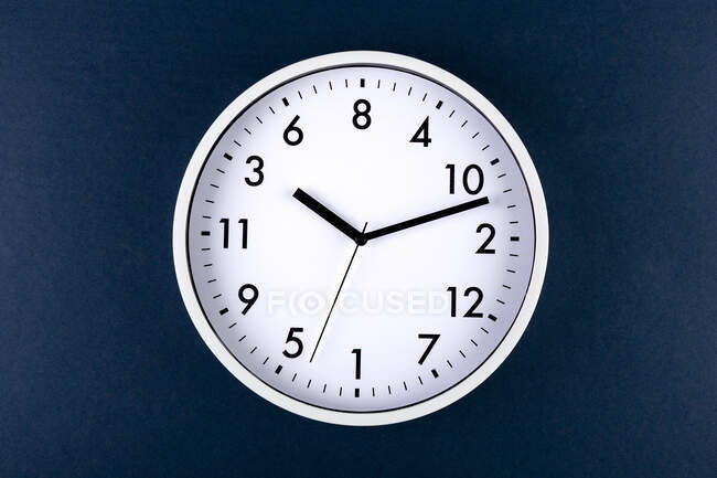 Runde geformte minimalistische Uhr mit Zahlen und Pfeilen auf buntem blauen Hintergrund — Stockfoto