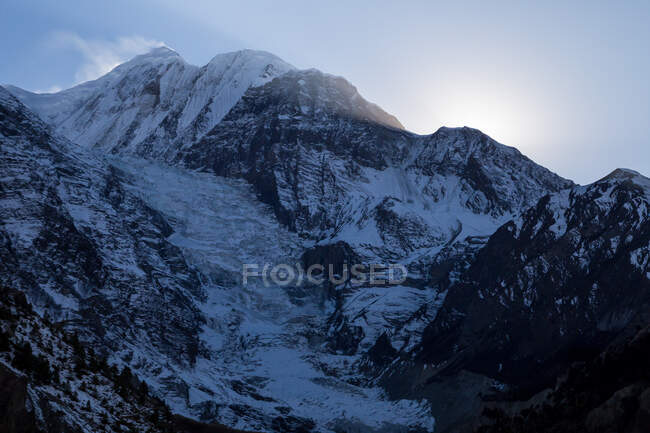 Высокие крутые склоны гор, покрытые снегом, расположенные в Гималаях, простираются под красочным небом Непала — стоковое фото