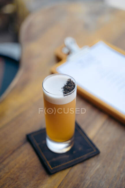 Високий кут склянки яєчного білого коктейлю з піною, розміщеною біля меню на дерев'яній барній стійці — стокове фото