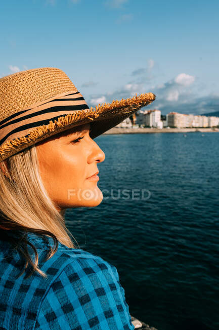 Бічний вид жінки-мандрівника в капелюсі споглядаючи нескінченне море в Сен-Жан-де-Луз Франції — стокове фото