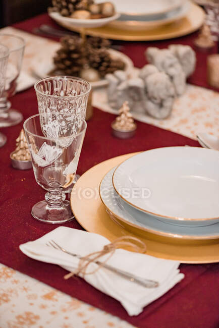Вид сверху на вилку на салфетке, связанную тройкой, расположенной рядом с тарелкой, и бокалы на столе, подаваемом к рождественскому ужину — стоковое фото