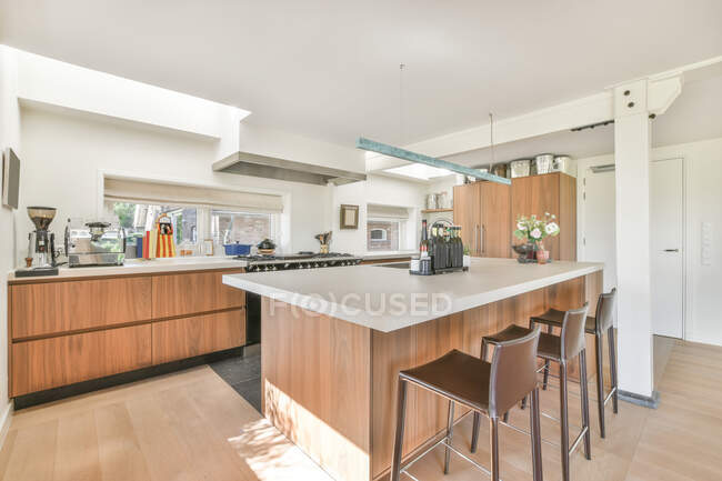Creative design of modern kitchen between tables with kitchenware in light house — Stock Photo