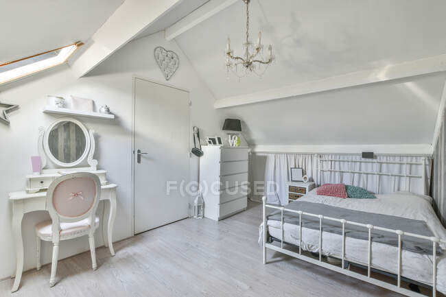 Weißes Interieur eines modernen Schlafzimmers mit bequemem Bett und hölzernem Schminktisch im Dachgeschoss des Hauses — Stockfoto