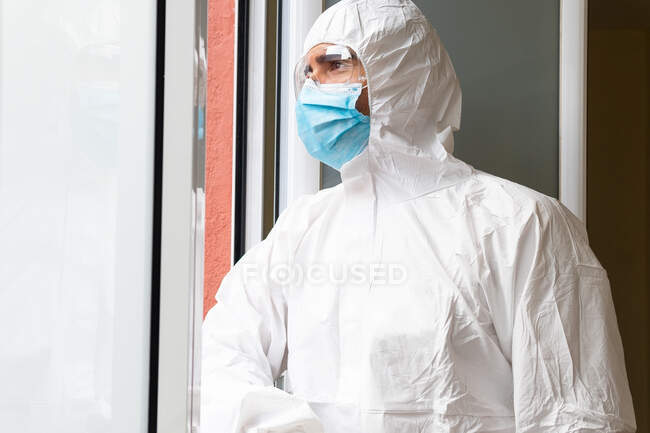 Vista laterale del medico maschio adulto premuroso in dispositivi di protezione individuale respirando aria fresca in ospedale — Foto stock