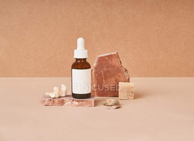 Kleine Flasche Schönheitsöl und natürliche handgefertigte Seifenstücke mit Bimsstein auf zweifarbigem Hintergrund — Stockfoto
