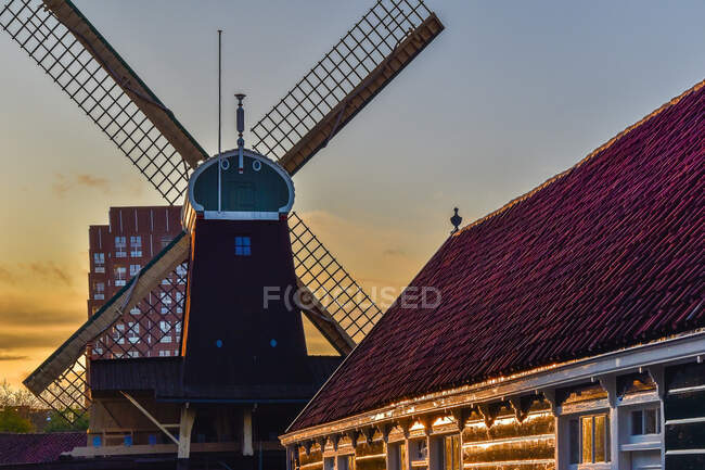 Vue imprenable sur le vieux moulin à vent en bois situé dans le village sur fond de ciel couchant — Photo de stock