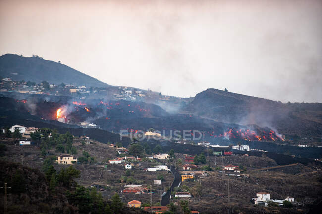 Lava quente e magma saindo da cratera enquanto arrasa casas da cidade. Erupção do vulcão Cumbre Vieja nas Ilhas Canárias de La Palma, Espanha, 2021 — Fotografia de Stock