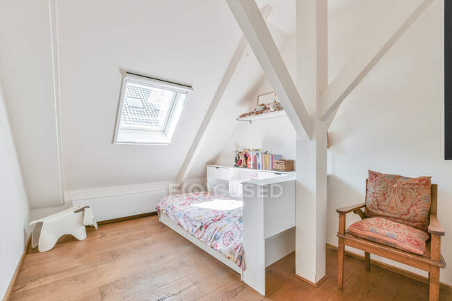 Interior do quarto com cama contra fezes pequenas e poltrona velha com almofadas ornamentais em casa no dia ensolarado — Fotografia de Stock