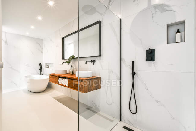 Design creativo del bagno con doppi lavabi sotto specchio lampade riflettenti e cabina doccia con pareti in vetro in casa — Foto stock