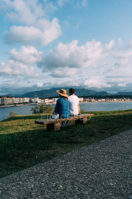 Back view of anonymous couple of tourists contemplating sea and mount under cloudy blue sky in Saint Jean de Luz — Stock Photo