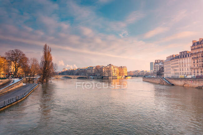 Historische Wohnhäuser am Ufer des plätschernden Flusses, der im Winter abends in Paris fließt — Stockfoto