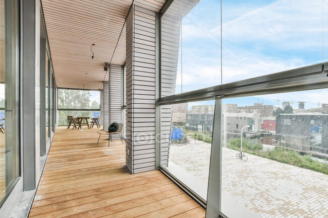 Интерьер балкона с деревянным столом против окон и колонн под потолком в доме — стоковое фото