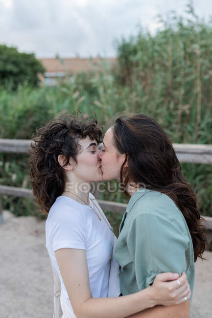 Вид збоку модна молода жінка з гомосексуальним улюбленим поцілунком на мосту — стокове фото