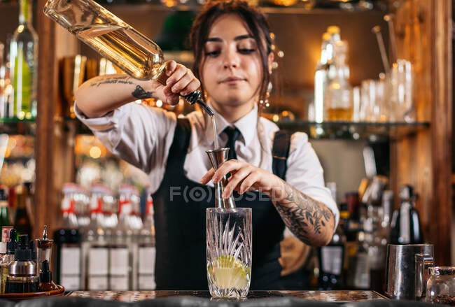 Femme barman verser du rhum dans le verre tout en préparant un cocktail Mojito rafraîchissant dans le bar — Photo de stock
