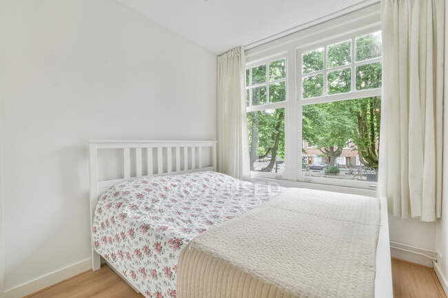 Intérieur minimaliste de la chambre à coucher avec lit confortable contre la fenêtre et les murs de lumière en journée — Photo de stock