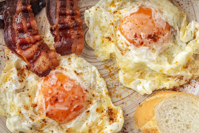 Gustose uova soleggiate con strisce di pancetta fritte sul piatto — Foto stock