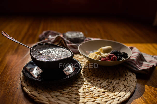 From above healthy chopped bananas and blackberries and strawberries served with milk with chia on wicker stand — Stock Photo
