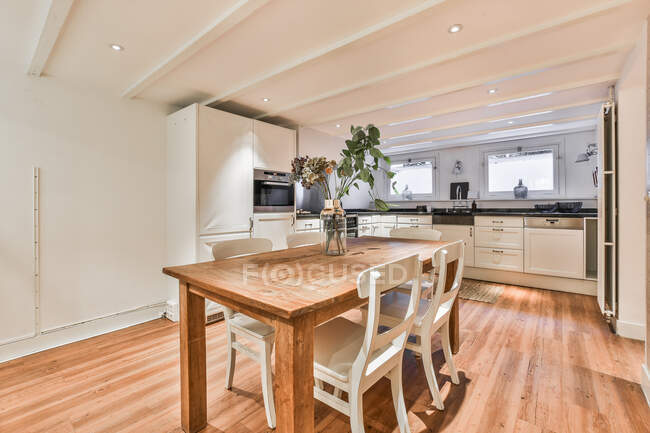 Сучасний інтер'єр просторої кухні з дерев'яним столом і стільцями в новій квартирі — стокове фото
