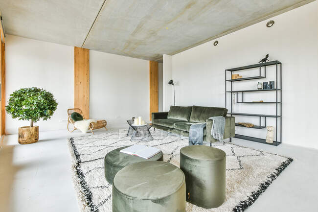 Сучасний інтер'єр вітальні з пуфами на диван і стіл на килимі з орнаментом у світлому будинку — стокове фото