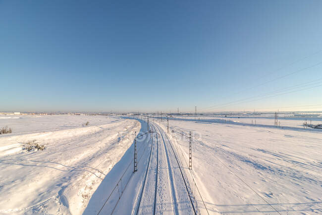 Drone view of train on railroad on snowy terrain under blue clear sky — Stock Photo