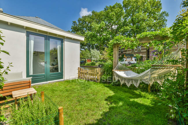 Terrazza di casa residenziale con piante verdi e amaca sotto il cielo blu nella giornata di sole — Foto stock