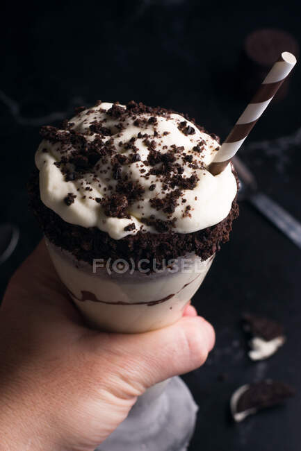 Crop anonymous person with tasty shake with whipped cream and chocolate cookies on top of jar — Stock Photo