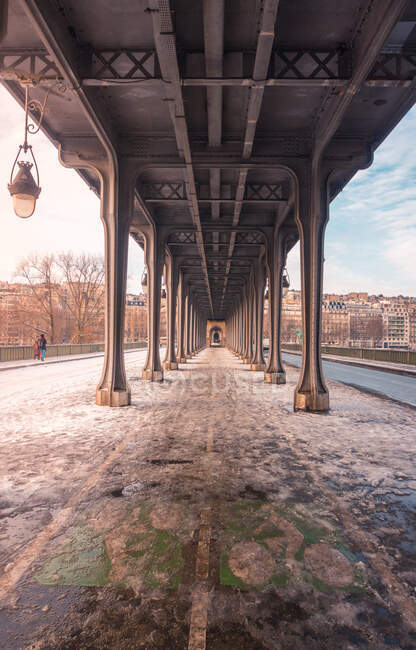 Pedestrians walking on sidewalk of bridge with bicycle path between posts in winter Paris — Stock Photo