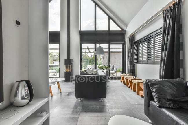 Interior da sala de estar colorida cinza espaçoso elegante decorado com sofás confortáveis perto de portas de vidro — Fotografia de Stock