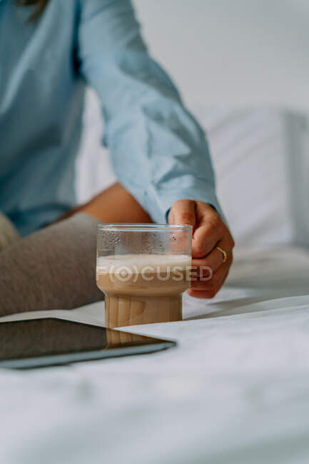 Врожай невизначена жінка в кільці з планшетом і чашкою смачної кави з молоком в спальні — стокове фото